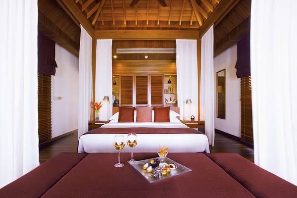 Schlafzimmer im Baros Maldives Resort mit Bett, Weinglas und Essenstablett