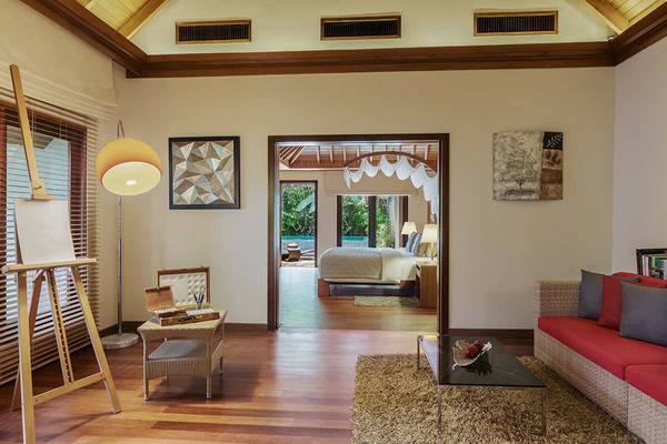 Wohnzimmer des Baros Maldives Resorts mit einem Bett im Hintergrund