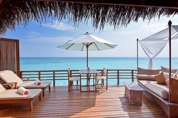 Der Balkon des Baros Maldives Resorts mit Blick auf das Meer und einem Tisch mit Sonnenschirm.