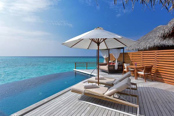 Ein Infinity-Pool mit Sonnenschirm und Holzterrasse im Baros Maldives Resort.