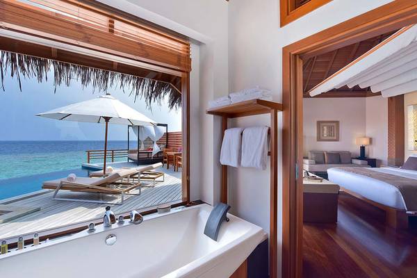 Suite im Baros Maldives Resort mit Meerblick, Badewanne und Terrasse mit Sonnenliegen.
