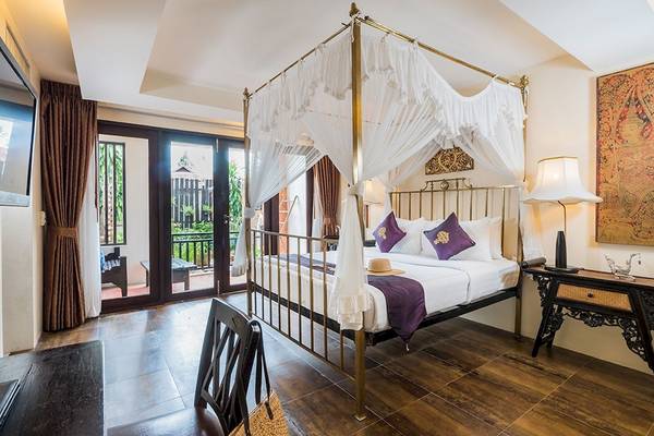 Schlafzimmer im Dara Samui Beach Resort mit einem Himmelbett, Balkon und Dekor.