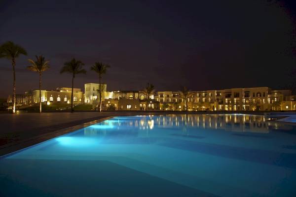 Nachtansicht des Salalah Rotana Resorts mit beleuchtetem Pool und Gebäuden im Hintergrund.