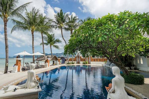 Außenpool des Dara Samui Beach Resort mit Statuen und Sonnenliegen.