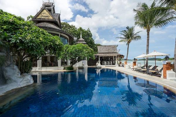 Außenbereich des Dara Samui Beach Resorts mit Swimmingpool, Lounge-Stühlen und Palmen.