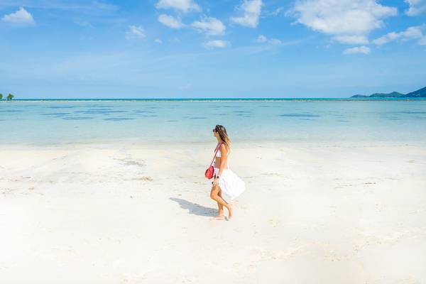 Frau am Strand von Dara Samui Beach Resort, mit weißem Kleid und rotem Handtasche.