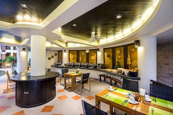 Innenansicht des Frühstücksbereichs im Dara Samui Beach Resort mit Tisch und Stühlen, Frühstücksbuffet und architektonischen Details.