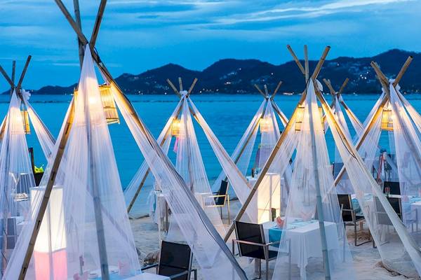 Strandrestaurant mit Tischdecken und Tipis bei Nacht mit Blick auf das Meer.