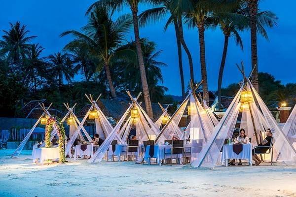 Dinner auf dem Strand im Dara Samui Beach Resort mit zeltartigen Strukturen und Palmen im Hintergrund.