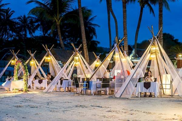 Das Dara Samui Beach Resort Strandrestaurant bei Nacht mit illuminierten Zelten und Gästen.