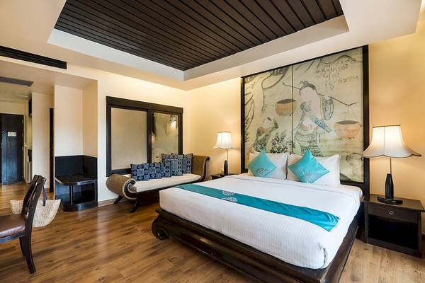 Schlafzimmer im Dara Samui Beach Resort mit einem großen Bett, zwei Nachttischen, Lampen und einer großen Wandmalerei.