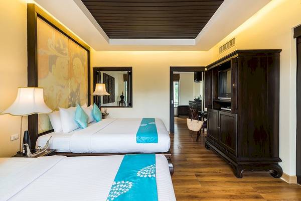 Innenansicht eines Doppelzimmers im Dara Samui Beach Resort mit zwei Betten, Dekor und M öbeln.