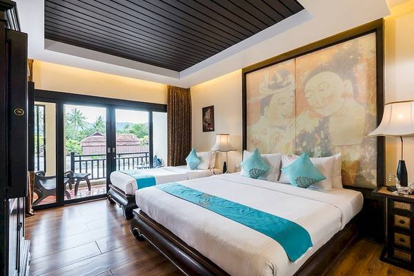 Zwei Betten in einem Zimmer im Dara Samui Beach Resort mit einem großen Wandbild, das einen Buddha darstellt.