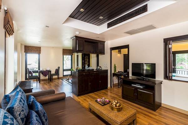 Wohnzimmer im Dara Samui Beach Resort mit Sofa, Fernseher und Esstisch.