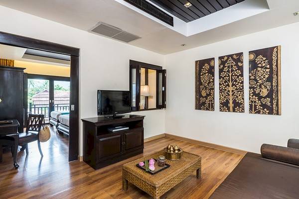 Wohnzimmer im Dara Samui Beach Resort mit Fernseher, Tisch und Couch.