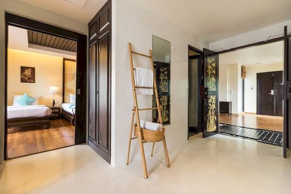 Innenansicht des Dara Samui Beach Resorts mit Holztür, Bambusständer und Schlafzimmer.