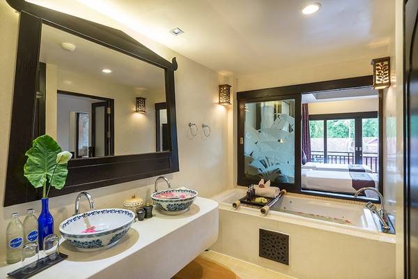 Badezimmer im Dara Samui Beach Resort mit zwei Waschbecken, Badewanne und Spiegel.