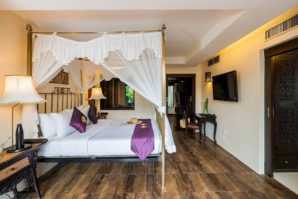 Ein Schlafzimmer im Dara Samui Beach Resort mit einem Himmelbett, Bettwäsche und einer Nachttischlampe.