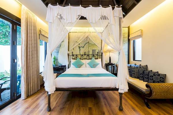 Schlafzimmer im Dara Samui Beach Resort mit einem Bett unter einem Baldachin und einer Couch.
