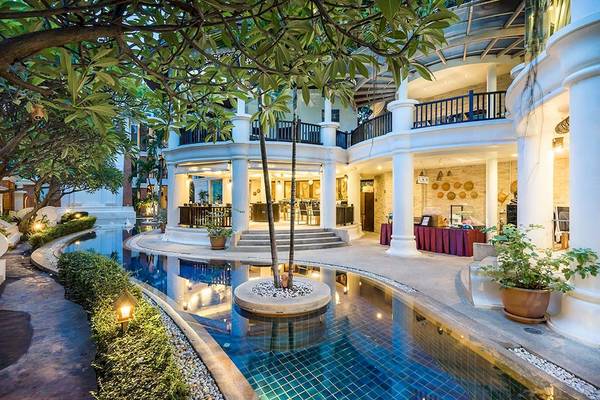 Außenansicht des Dara Samui Beach Resorts mit Pool, Bäumen und einem weißen Gebäude.