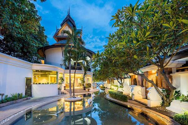 Außenansicht des Dara Samui Beach Resort bei Nacht mit beleuchtetem Gebäude, Wassergraben und beleuchteten Bäumen.