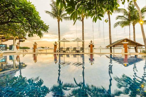 Außenbereich des Dara Samui Beach Resort mit Pool, Liegestühlen und Palmen.