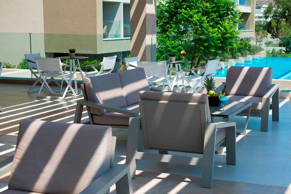 Lounge-Terrasse im Amada Colossos Resort mit Sitzmöbeln und Swimmingpool im Hintergrund.