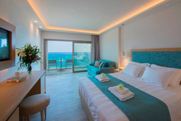 Amadas Colossos Resort Zimmer mit Meerblick, Doppelbett, Wohnzimmer, Balkon, Sofa, Tisch und Stühlen.