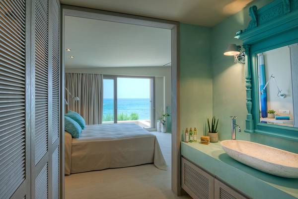 Blick in ein Zimmer im Amada Colossos Resort mit Bett und Badezimmer mit Meerblick.