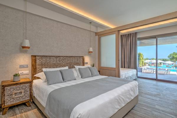 Ein elegantes Hotelzimmer im Amada Colossos Resort mit einem Bett, einem Nachttisch und einer Terrasse mit Poolblick.