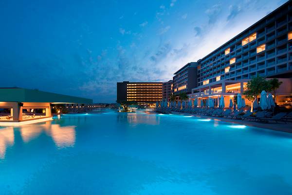Am Abend beleuchteter Pool des Amada Colossos Resorts mit Loungebereich und Hotelgebäude im Hintergrund.