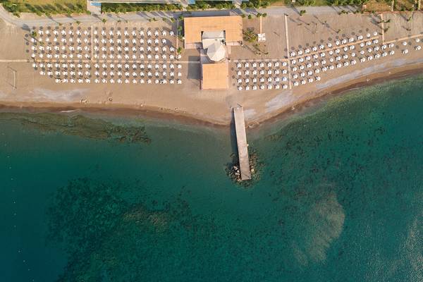 Luftaufnahme des Amada Colossos Resorts am Strand mit vielen Sonnenschirmen und einem Steg im Wasser.