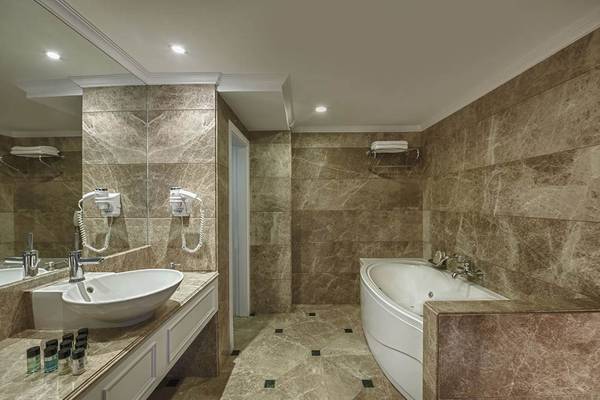 Badezimmer im Delphin Diva Premiere Hotel mit Badewanne und Waschbecken.
