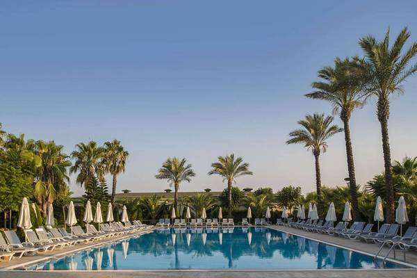 Außenpool des Delphin Diva Premiere Hotels mit weißen Sonnenliegen und Sonnenschirmen.