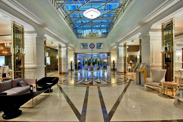 Lobby des Delphin Diva Premiere Hotels mit Marmorboden, Kronleuchtern und Sitzbereichen.