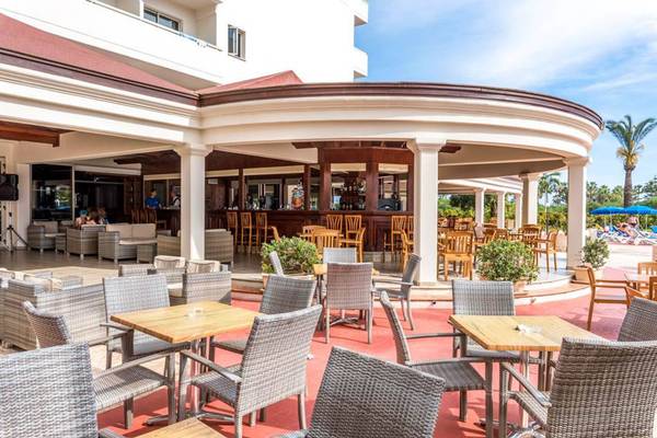 Außenbereich des Nissiana Hotels mit Bar, Tischen und Stühlen unter einer Pergola