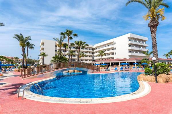 Außenpool des Nissiana Hotels mit Brücke und Sonnenschirmen.