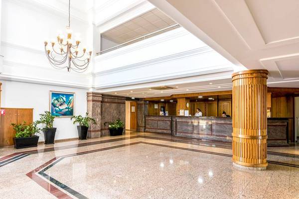 Eingangsbereich des Nissiana Hotels mit Rezeptionstresen, Kronleuchter und Pflanzen.