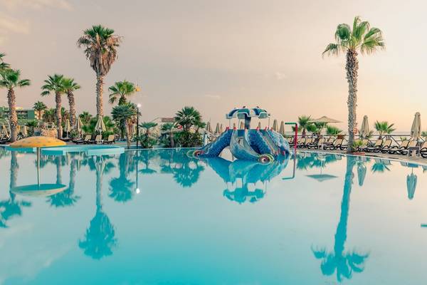Ein Swimmingpool im Star Beach Village & Water Park mit Palmen und Sonnenliegen.