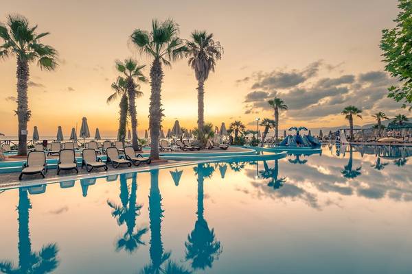 Sonnenuntergang am Pool des Star Beach Village & Water Park mit Liegestühlen und Palmen