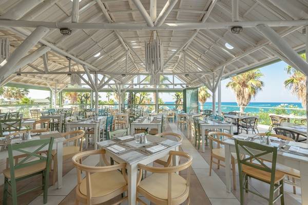 Innenansicht des Restaurants im Star Beach Village & Water Park mit Blick auf das Meer und Palmen.