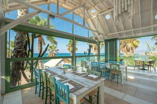 Innenansicht eines Restaurants im Star Beach Village & Water Park mit Tischen, Stühlen und Blick auf das Meer.