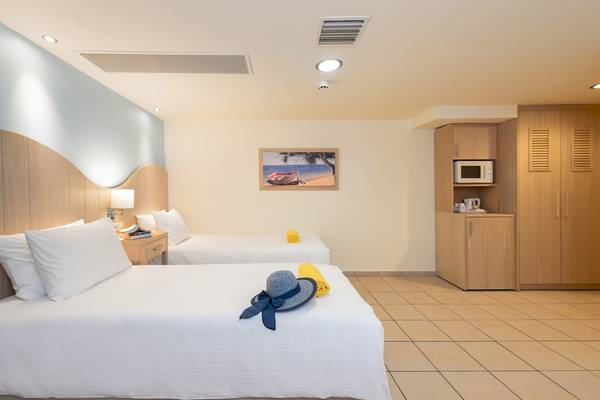 Zimmer im Star Beach Village & Water Park Hotel mit zwei Betten, weißen Laken, Kissen und Decken.