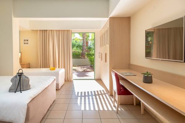 Innenansicht eines Zimmers im Star Beach Village Hotel mit zwei Betten, einer Tasche und einem Schreibtisch.
