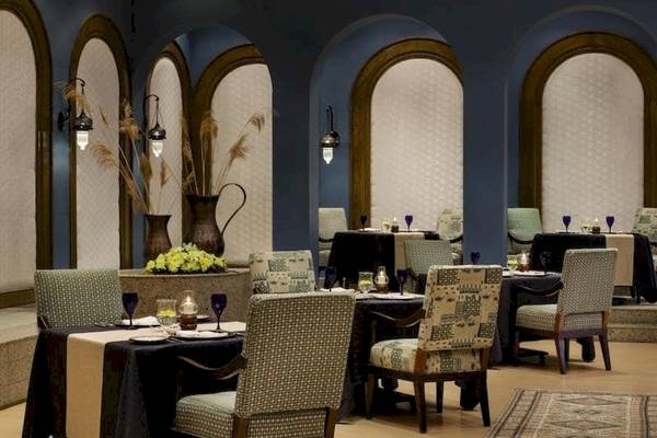 Innenraum des Restaurants im Oberoi Beach Resort mit gedeckten Tischen und gemusterten Stühlen.