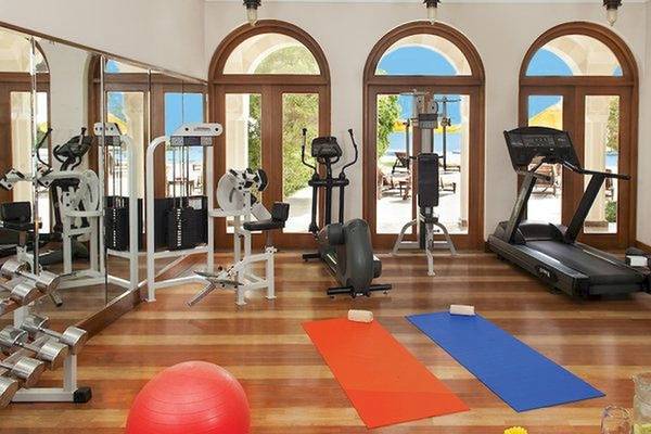 Fitnessstudio im Oberoi Beach Resort mit Geräten, Matten und einer Aussicht auf das Meer.