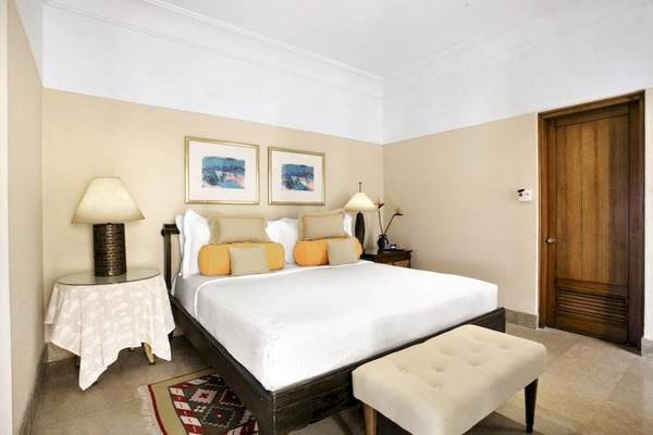 Schlafzimmer im Oberoi Beach Resort mit einem großen Bett, Nachttischen und Lampen.