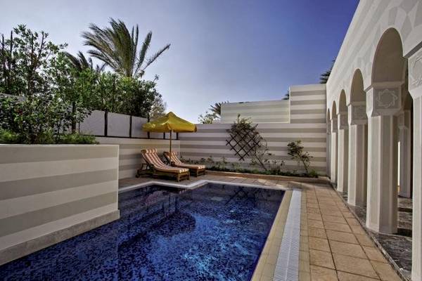 Privater Poolbereich im Oberoi Beach Resort mit Lounge-Stuhl und Sonnenschirm.
