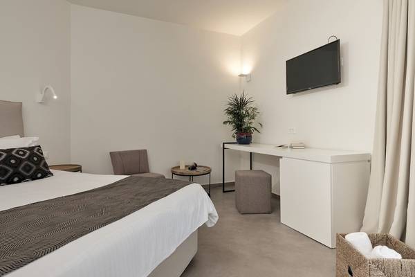 Innenansicht eines Zimmers im Caravel Hotel mit Bett, Schreibtisch, Stühlen und Fernseher.