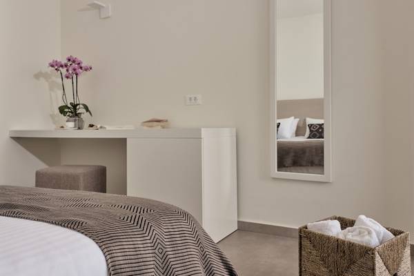 Schlafzimmer im Caravel Hotel mit Bett, Nachttisch, Spiegel und Wäschekorb.